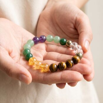 Money Magnet Bracelet featuring Green Aventurine, Jade, Citrine, Tiger's Eye, Clear Quartz, Golden Pyrite and Amethyst crystals placed on a hand