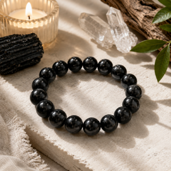 Black Tourmaline crystal bracelet displayed with raw Black Tourmaline, Clear Quartz, a candle, and natural greenery.