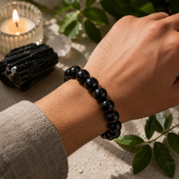 Black Tourmaline crystal bracelet with polished black beads worn on the wrist in a natural setting.