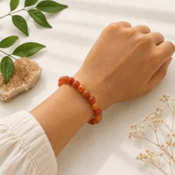 Carnelian crystal bracelet worn on the wrist against a soft white background with natural greenery
