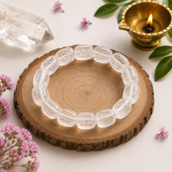 Clear Quartz Crystal Bracelet displayed on a natural wooden base with brass diya and greenery