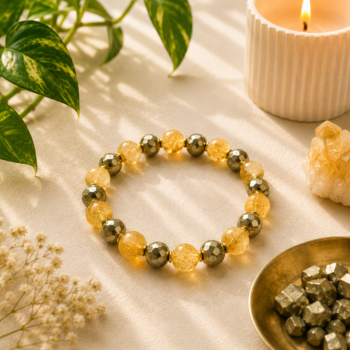 Citrine and Pyrite bracelet displayed with golden crystals, greenery and a candle in warm natural light