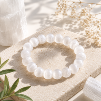 Selenite crystal bracelet with luminous white round beads displayed on a natural stone surface in soft sunlight