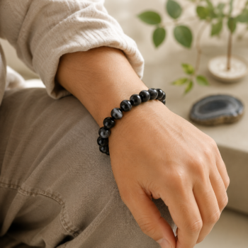 Suleimani Hakik Black Agate crystal bracelet worn on a wrist resting gently on the knee