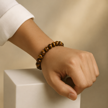 Tiger Eye Crystal Bracelet with polished brown and golden beads worn on the wrist against a warm beige background.