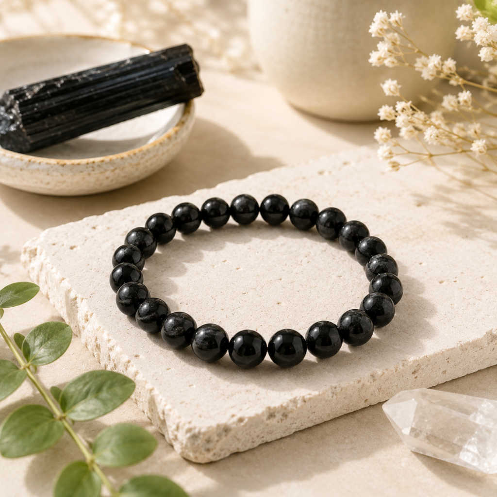 Natural Black Tourmaline bracelet displayed with raw Black Tourmaline and healing crystals in a minimalist setting for grounding and everyday protection.